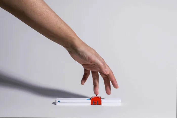 A hand placing a drop of blood from a fingertip onto a dried blood spot collection device