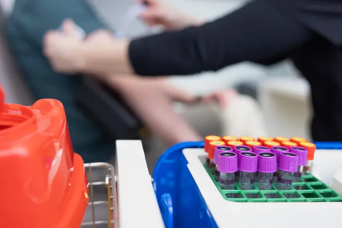 A venous blood draw in progress, with a rack of capped blood collection tubes in the foreground